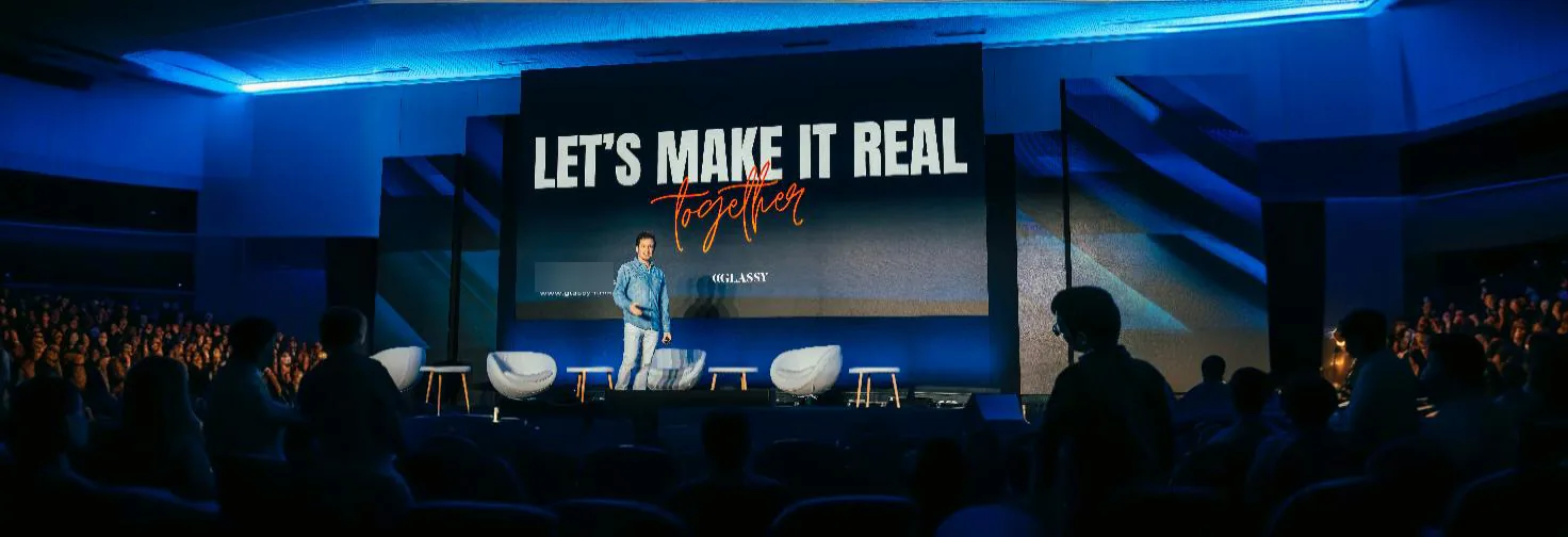 Yago de la Sotilla en el escenario ante un auditorio lleno, con la frase «Let’s make it real together» en pantalla
