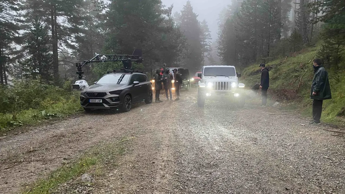 Coche cámara y equipo en una pista de bosque con niebla, rodaje de Jeep